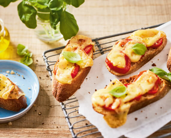 Überbackenes Brot mit Käse, Tomaten und Basilikum