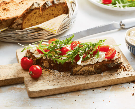 Bauernbrot mit Frischkäse und Tomaten-Rucola-Topping