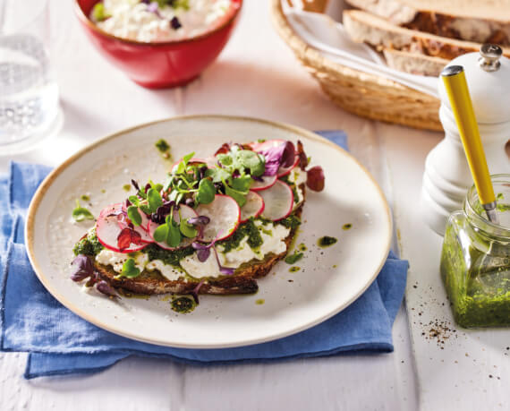 Brot mit körnigem Frischkäse, grünem Pesto und Radieschen