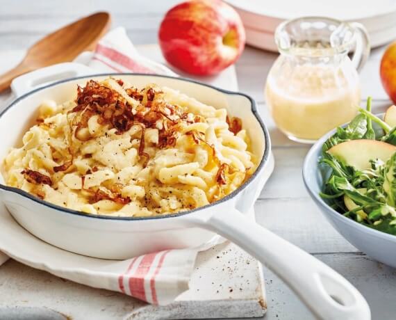 Allgäuer Käsespätzle mit geschmelzten Zwiebeln an fruchtigem Rucola-Salat