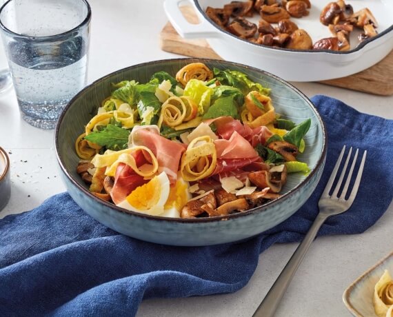 Pilz-Salat an Pfannkuchen-Streifen mit Käse und rohem Schinken
