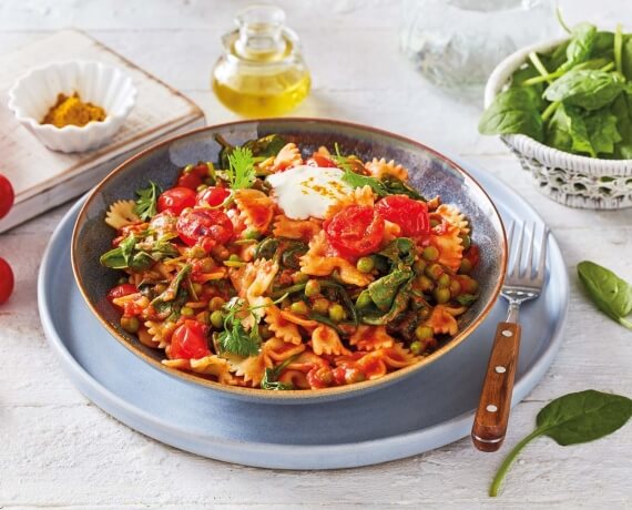 Farfalle in Curry-Tomatensauce mit grünen Erbsen und Spinat