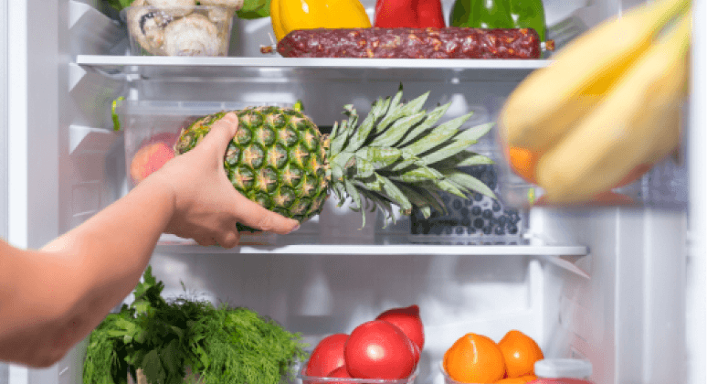 Frau legt Obst in Kühlschrank