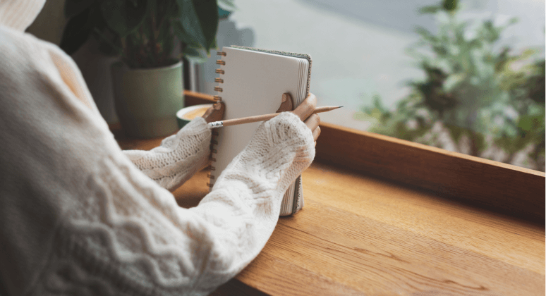 Junge Frau mit Notizbuch am Fenster