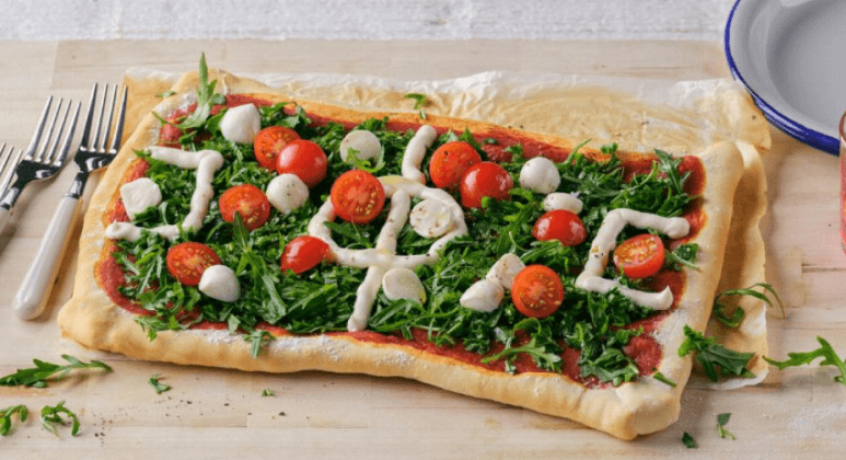 Fußball-Pizza mit Rucola, Cherrytomaten, Parmesan