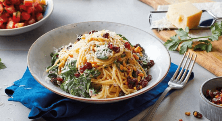 Spaghetti zu Rahm Spinat mit Pinienkernen und Rosinen an Tomatensalat
