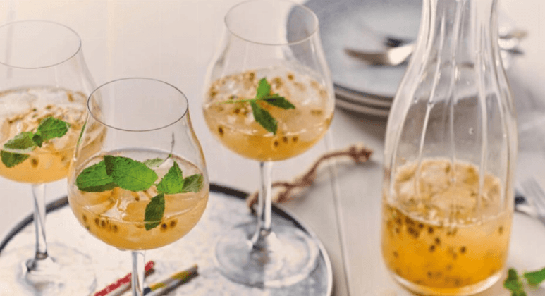 Maracuja-Ingwer-Limonade mit Minze im Glas mit Eiswürfeln und Krug