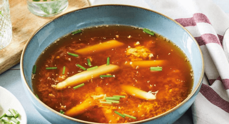Gemüsebrühe mit weißem Spargel, frischen Kräutern und gestocktem Ei