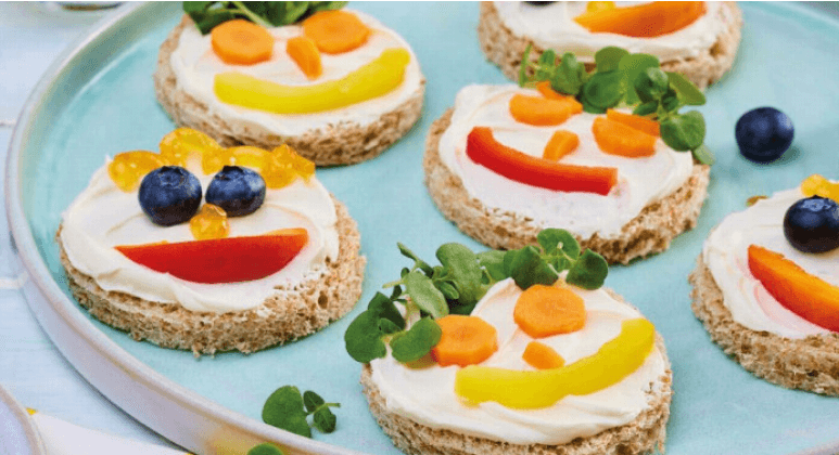 Vollkorntoast mit Gesichtern aus Paprika, Karotten und Heidelbeeren